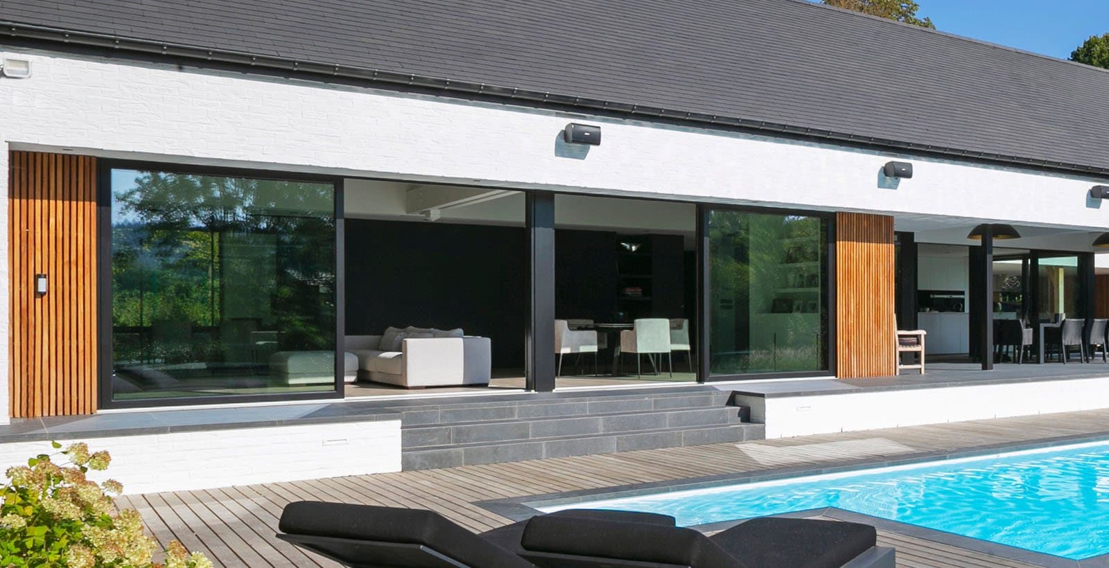 Villa de plain-pied avec grandes baies coulissantes en bois au bord d’une piscine