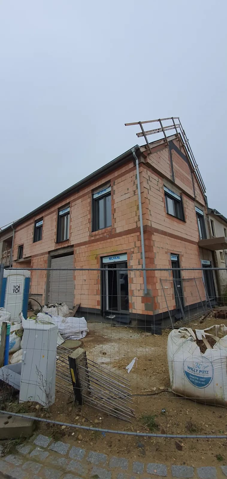 Façade de maison neuve avec fenêtres posées, avant enduit