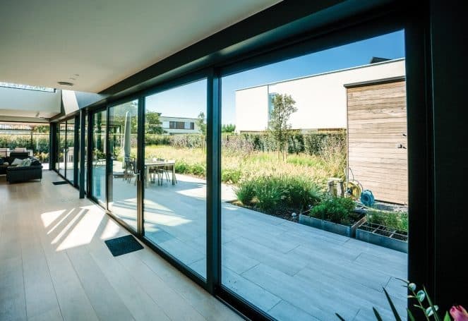 Baie coulissante en aluminium ouverte sur une terrasse et une piscine
