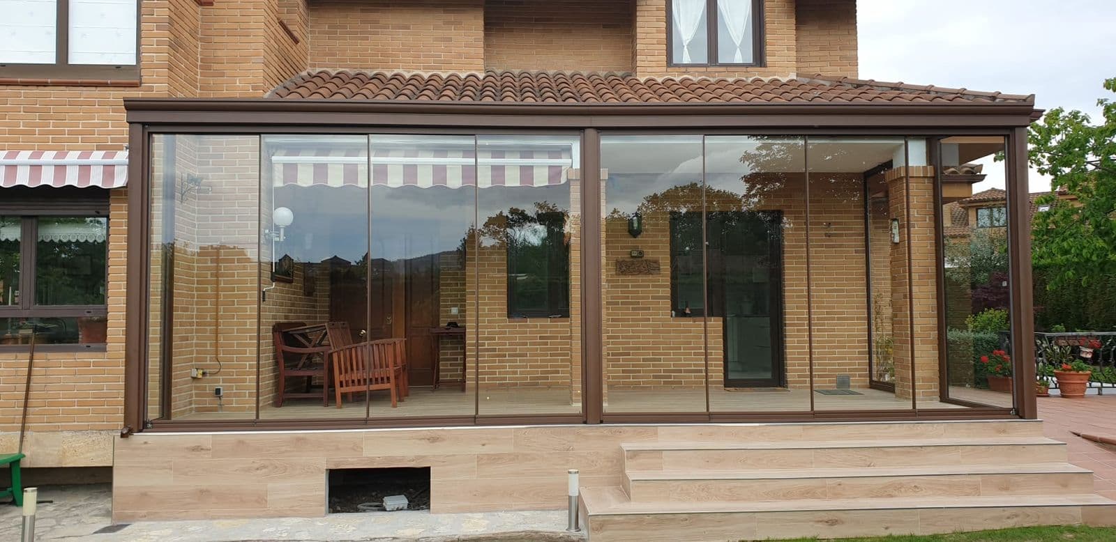 Maison avec pergola et terrasse fermée de verre