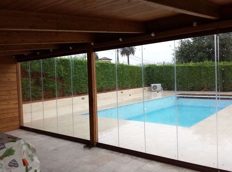 Pergola fermée de rideaux de verre au bord d’une piscine