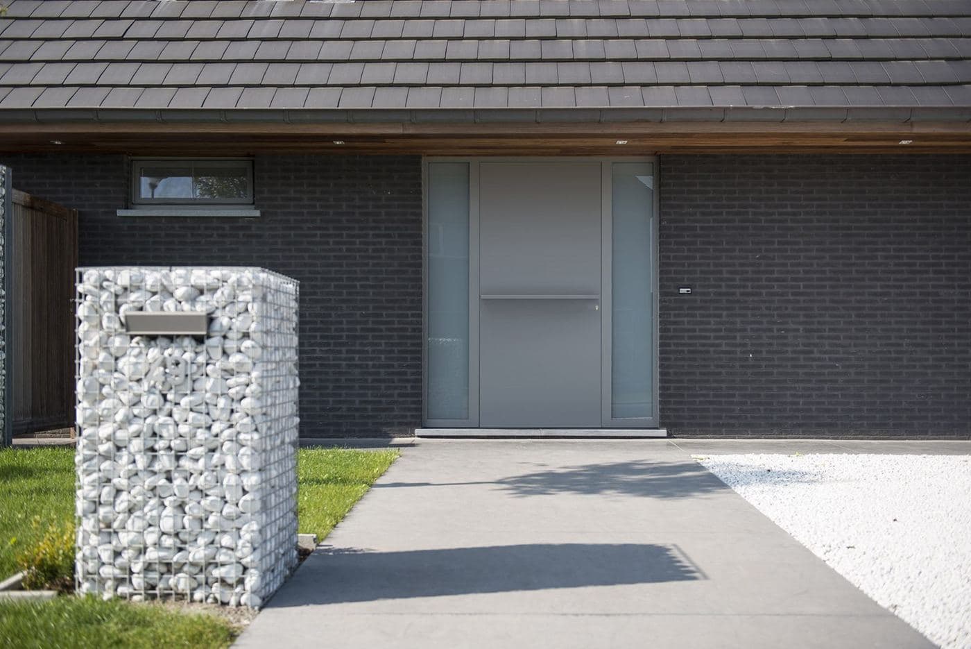 Maison moderne en brique sombre avec porte d’entrée Frager grise