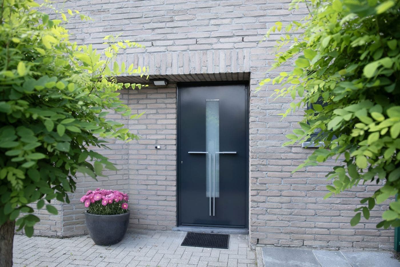 Porte d’entrée moderne bleu foncé sur une façade en brique claire