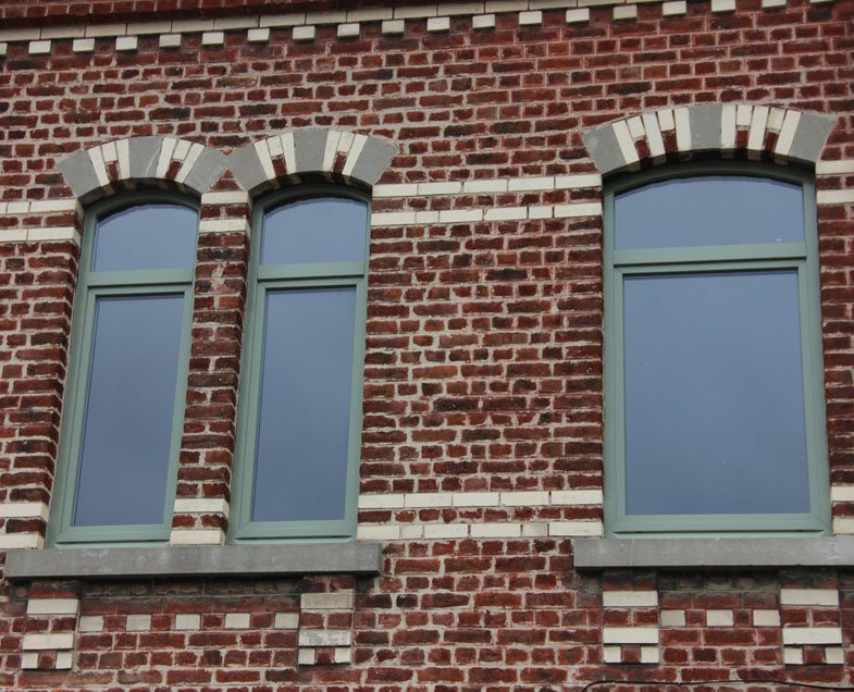 Façade en brique ancienne avec fenêtres bois cintrées vert-de-gris refaites sur mesure en rénovation